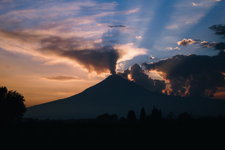 Stunning image of Popocatepetl Volcano in Mexico with an ash and vapor column at sunset, framed by...