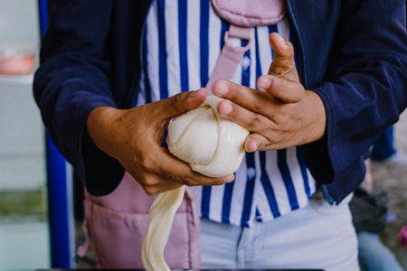 Close-up of hands folding and stretching fresh cheese dough strands, creating a traditional...