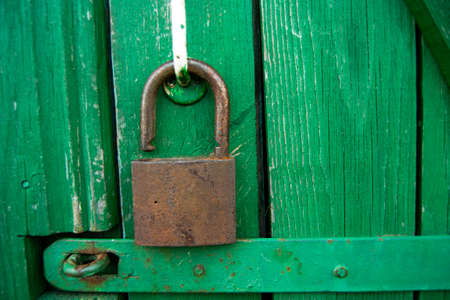 Old grungy wooden green door with rusted open padlock. Garage or barn door in rustic style with...