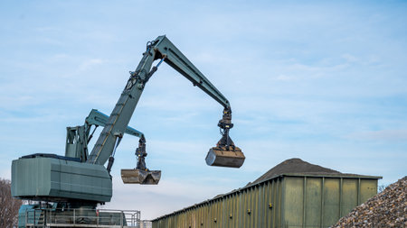 Big excavator working by handling pebbles from the pile of stones to container. Working machine in...