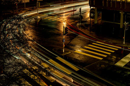 Crosswalk at night. Top view of car light trails over street in rainy day. Long exposure. Lausanne,...