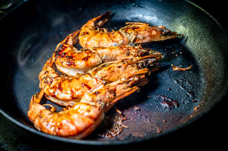 Grilled prawn in a frying pan on a dark background. Seafood appetizer. Preparation of delicious food.の写真素材