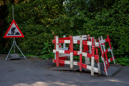 Road work sign under construction.Caution symbol. Red and white triangle safety sign and barriers warns about roadworks. Lausanne, Switzerland.の写真素材