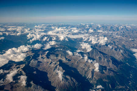 Aerial view of swiss alps. View of mountain and white cloud from the plane window. Tranquil scene.の写真素材