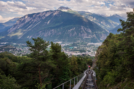 Crans Montana, Valais Canton, Switzerland - 15 July 2023: One red Swiss funicular from Sierre to Crans Montana. Public transport cable railway with scenic view over the city and mountain.のeditorial素材