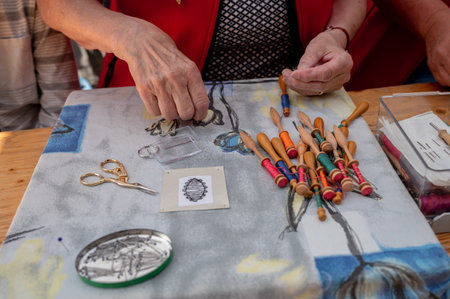 Hands of people preparing and making bobbin lace. Colorful lace threads. Leisure activity.