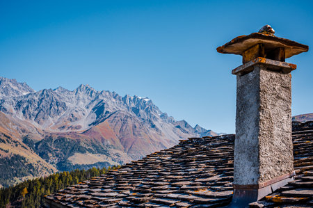 Mountain, chimney and stone tile roof in autumn. Liddes, Valais Canton, Switzerland.の写真素材