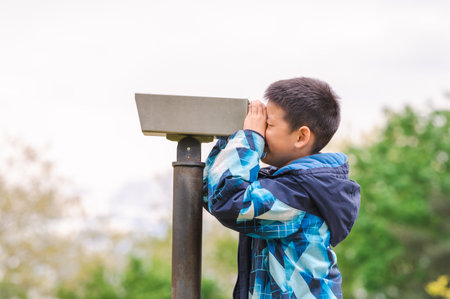One boy looking in telescope in park. Tourists on observation deck.の写真素材