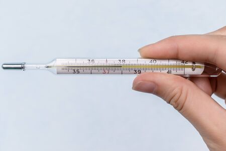 Human hand holding medicine healthcare thermometer. High temperature 38 on the mercury thermometer...