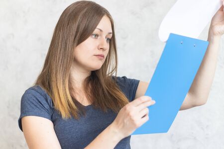 Attractive young girl with clipboard folder with blank white sheet of paper. Modern businesswoman...