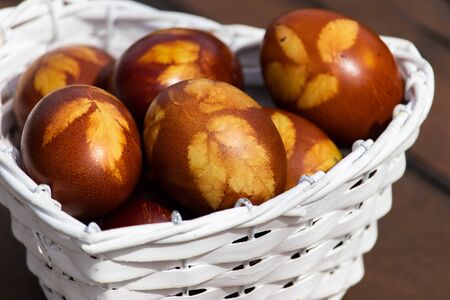 Easter eggs colored with onion husks in a white wicker basket in shape of heart. The old traditional...