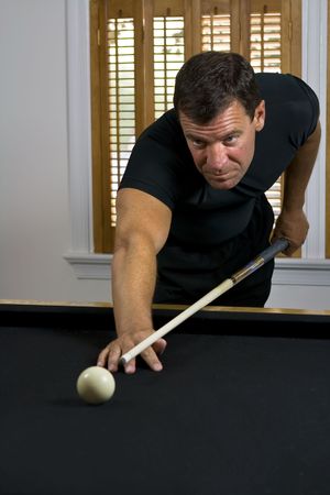 Man lining up the cue ball to break the billiards on the other end of the pool table.