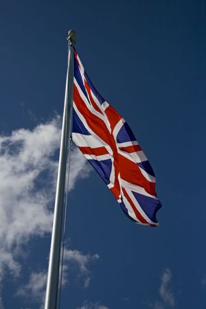 British flag blowing in the wind with clouds in the background.の写真素材