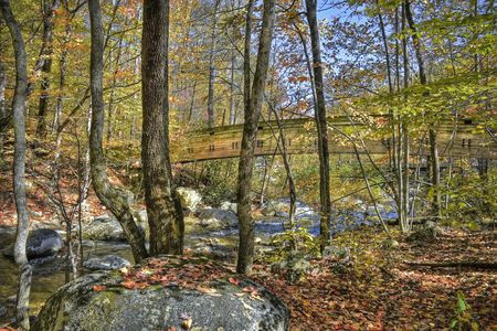 Long wooden bridge crossing a mountain stream viewed during the fall.