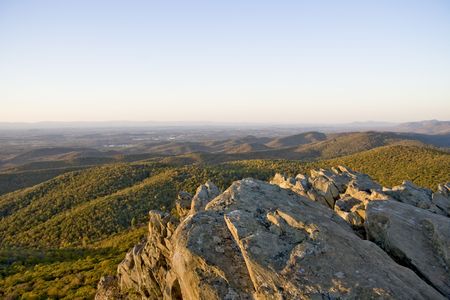 Rock structure over looking autumn mountain range as the sun sets.の写真素材