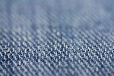 Macro textured background of blue colored jean material.