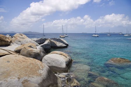 Rocky shoreline of the virgin islands and sailboats anchored in the water.の写真素材