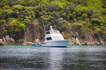 Large luxurious fishing boat anchored next to tropical island.の写真素材