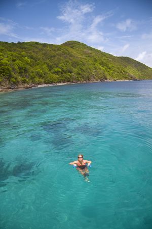 Young woman floating in crystal clear tropical water next to island.の写真素材