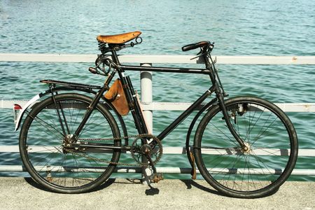 Antique looking bicycle parked beside a lake.の写真素材