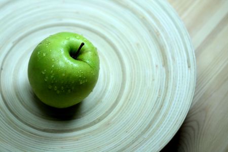 Green apple on a wooden tray with water droplets. Concept: Health. Shallow DOF.の写真素材