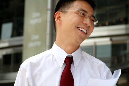 Good looking asian business man smiling with folder in hand.