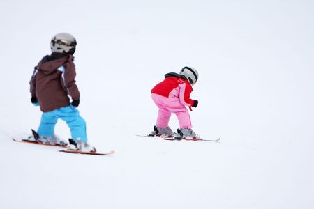 Winter scene with two kids skiing down a slope.の写真素材