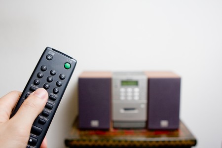 Hand holding a remote control pointing at a cd player