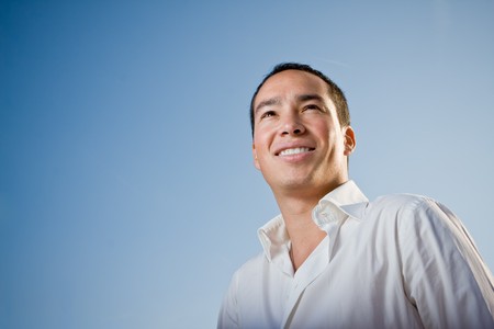 Youth standing against blue sky looking forwardの写真素材