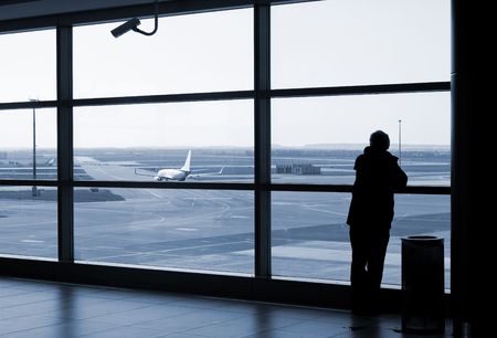 Airport lounge or waiting area with business man standing looking outside of window towards control towerのeditorial素材