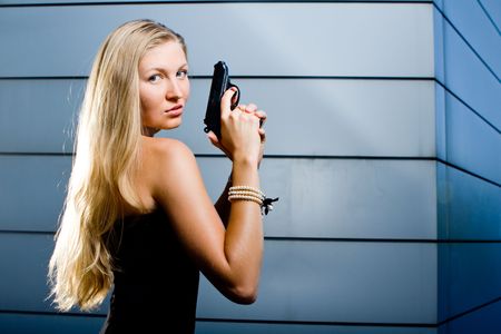 Sexy blonde woman as a secret agent spy holding hand gun firearmの写真素材