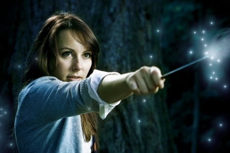 Teenage wizard girl with magic wand casting spells in a enchanted fantasy forestの写真素材