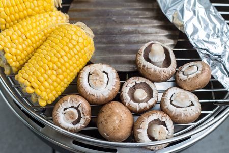 Bright yellow corn with wild mushrooms being grilled on the barbeque BBQの写真素材