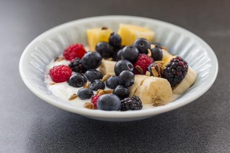 Plate of mixed fruits with yogurt, raspberry, blueberry, banana, gooseberryの写真素材