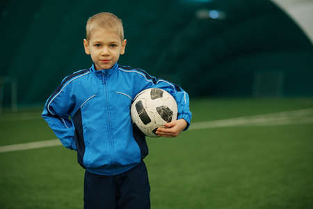 The boy holds a football having a rest from trainingの写真素材