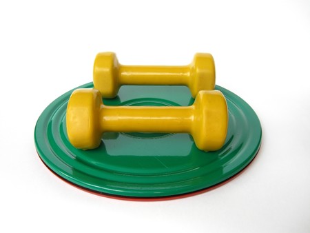 a couple of yellow dumbbells on the green roll disk の写真素材