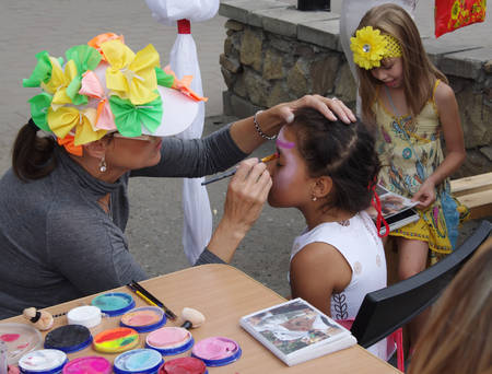 Omsk, Russia - August 03, 2014: painter draws painting on girl's faceのeditorial素材