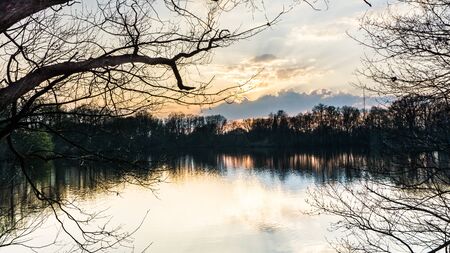 landscape with lake surrounded by trees at sunsetの写真素材