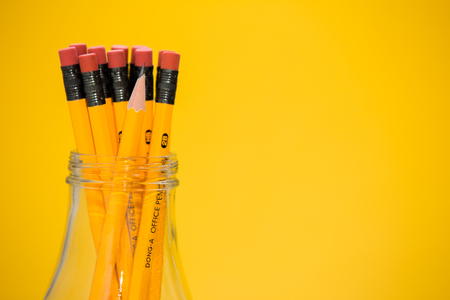 The pencils in a glass jar, yellow backgroundの写真素材