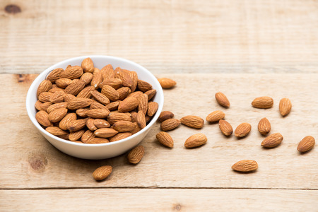 Almonds in a white cup rests on a wooden tableの写真素材