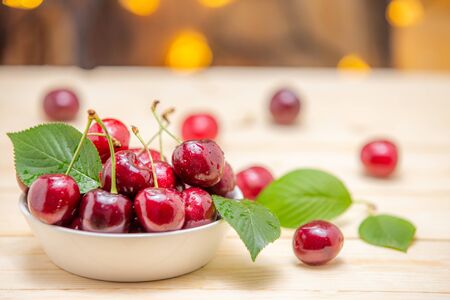Fresh cherries in the white bowl on wood tableの写真素材