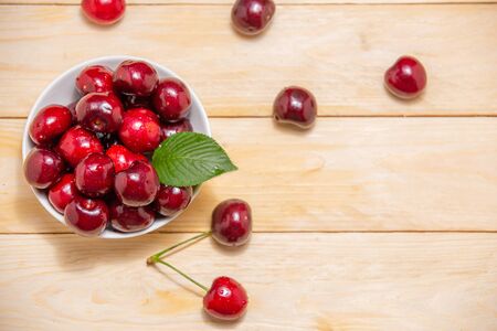 Top view fresh cherries in the white bowl on wood tableの写真素材