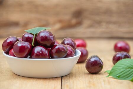 Fresh cherries in the white bowl on wood tableの写真素材