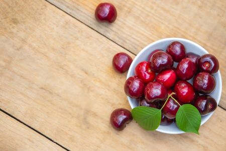 Top view fresh cherries in the white bowl on wood tableの写真素材