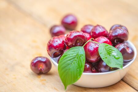 Top view fresh cherries in the white bowl on wood tableの写真素材