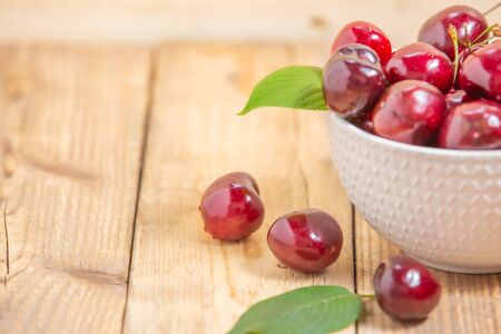 Fresh cherries in the white bowl on wood tableの写真素材