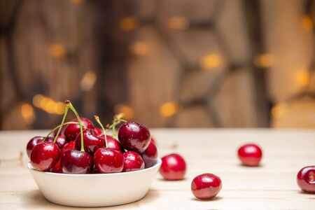 Fresh cherries in the white bowl on wood tableの写真素材