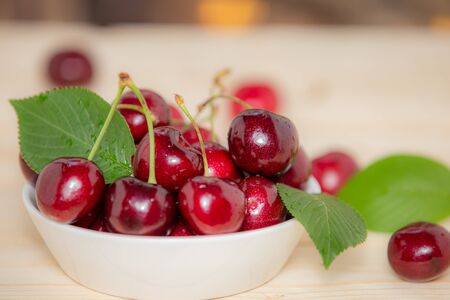 Fresh cherries in the white bowl on wood tableの写真素材