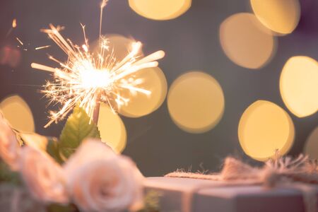Rose flower, gift box, sparkler, on wooden table with bokeh backgroundの写真素材