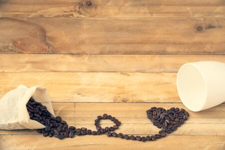 Sack beans coffee with a coffee heart shape on wooden backgroundの写真素材